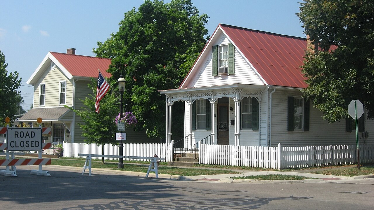 Historic residential houses with red tin roofs and decorative white picket fences along North High Street in Canal Winchester.