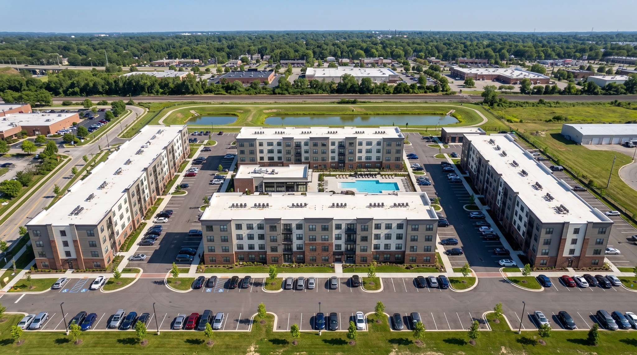 Oblique aerial drone photograph of the proposed Grandview Crossing FCEO apartment complex at 966 Dublin Road, featuring four four-story residential buildings, a central clubhouse and pool, surface parking, and surrounding landscape.