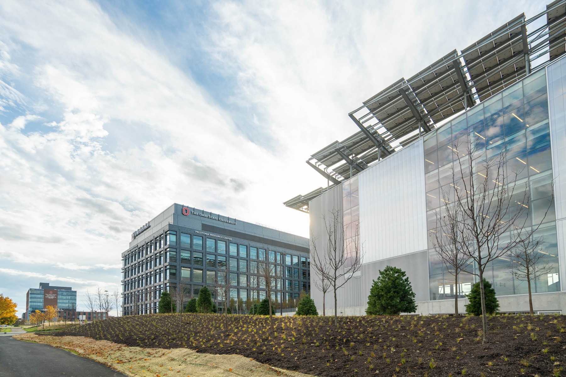 Exterior view of Ohio State University's Innovation District facilities including the Pelotonia Research Center under a partly cloudy sky.
