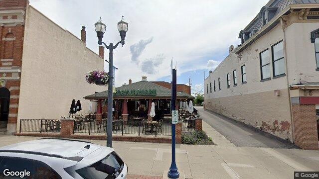 Street view of the Old Bag of Nails Pub exterior at 66 N. Sandusky St. in downtown Delaware, Ohio, showing the front patio, green roof overhang, and building sign.