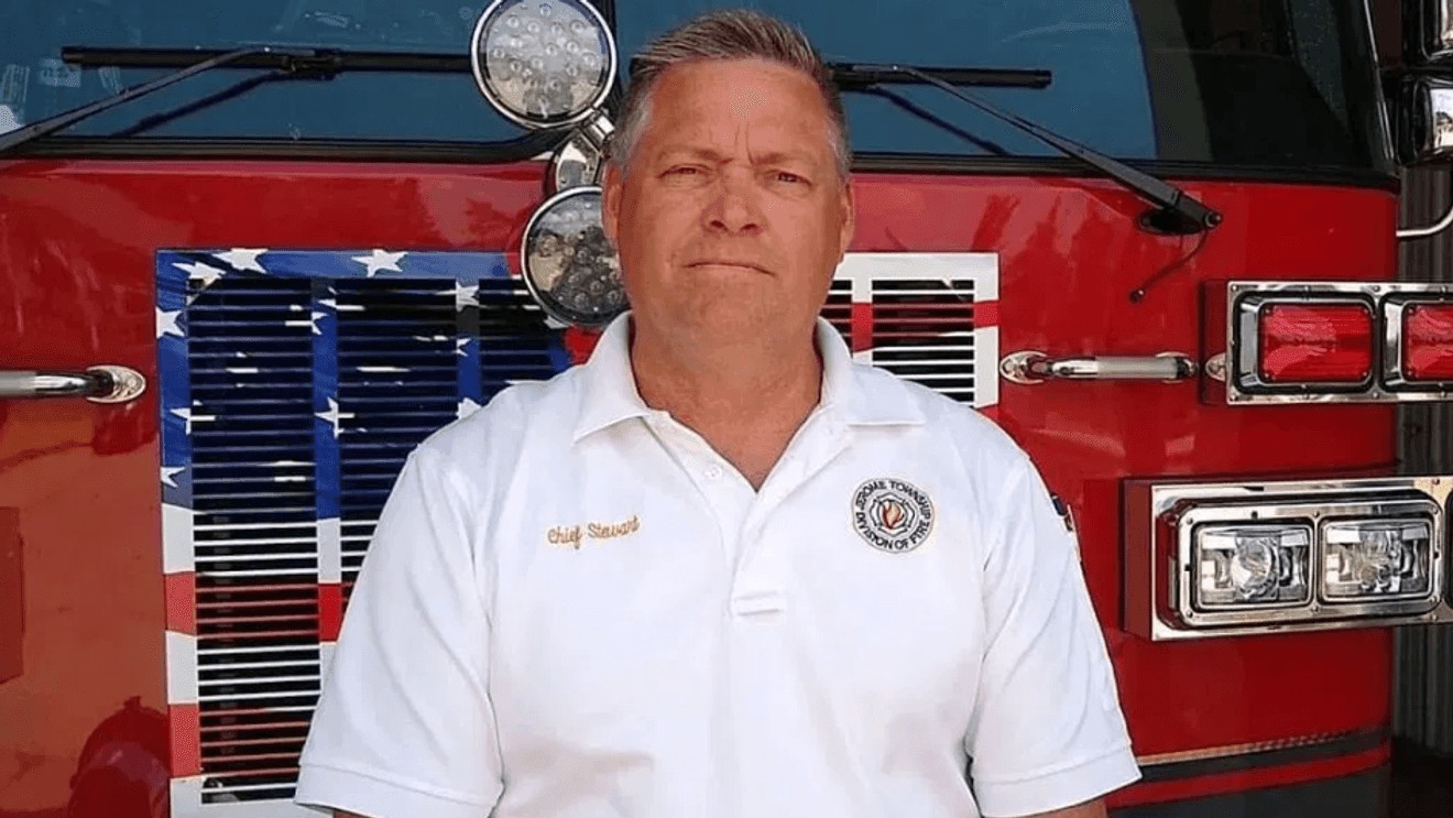 Medium portrait of Fire Chief Doug Stewart wearing a white Jerome Township Division of Fire polo shirt in front of a red fire truck.