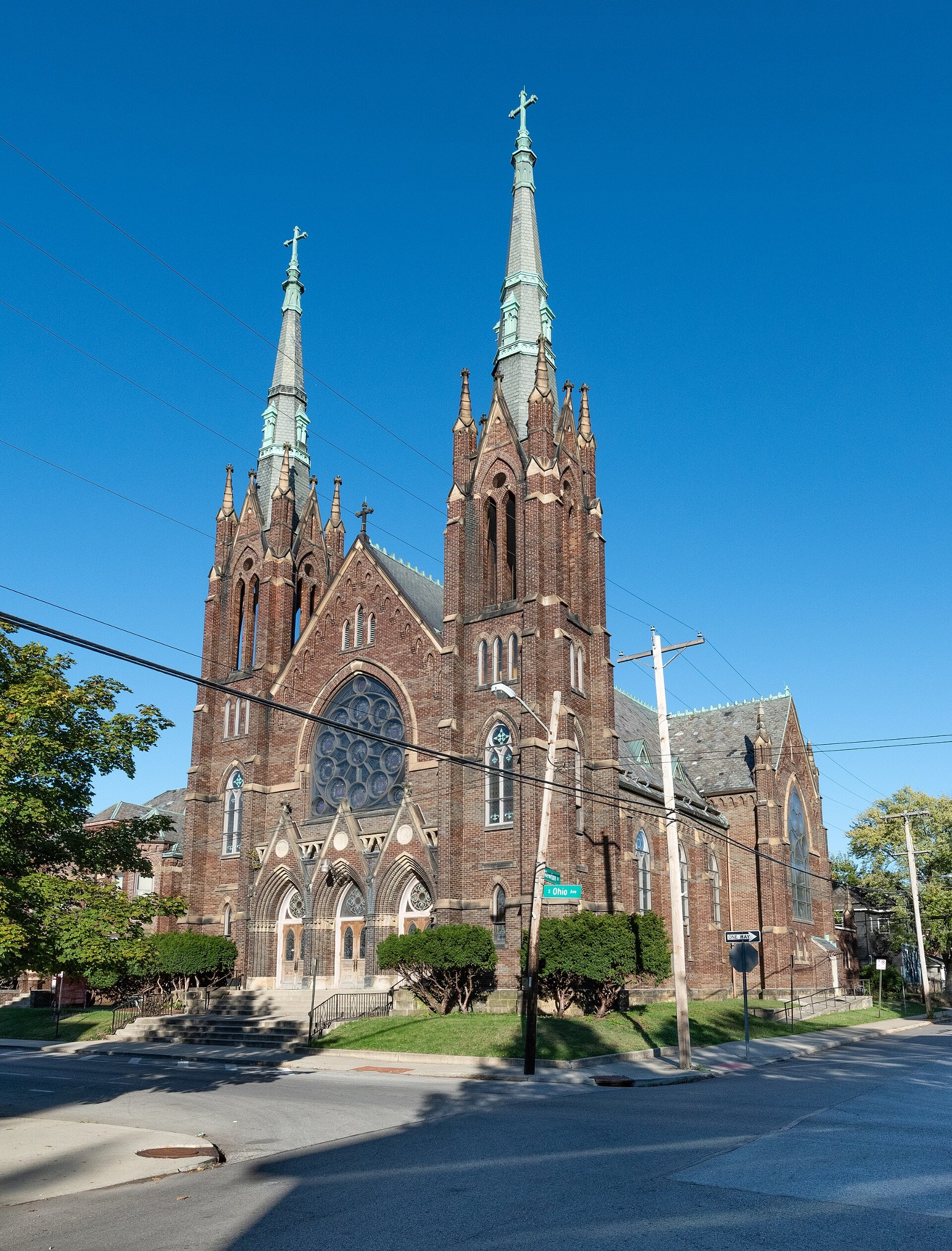 Exterior view of St. John the Evangelist Catholic Church with twin Gothic spires and vitrified brick facade.