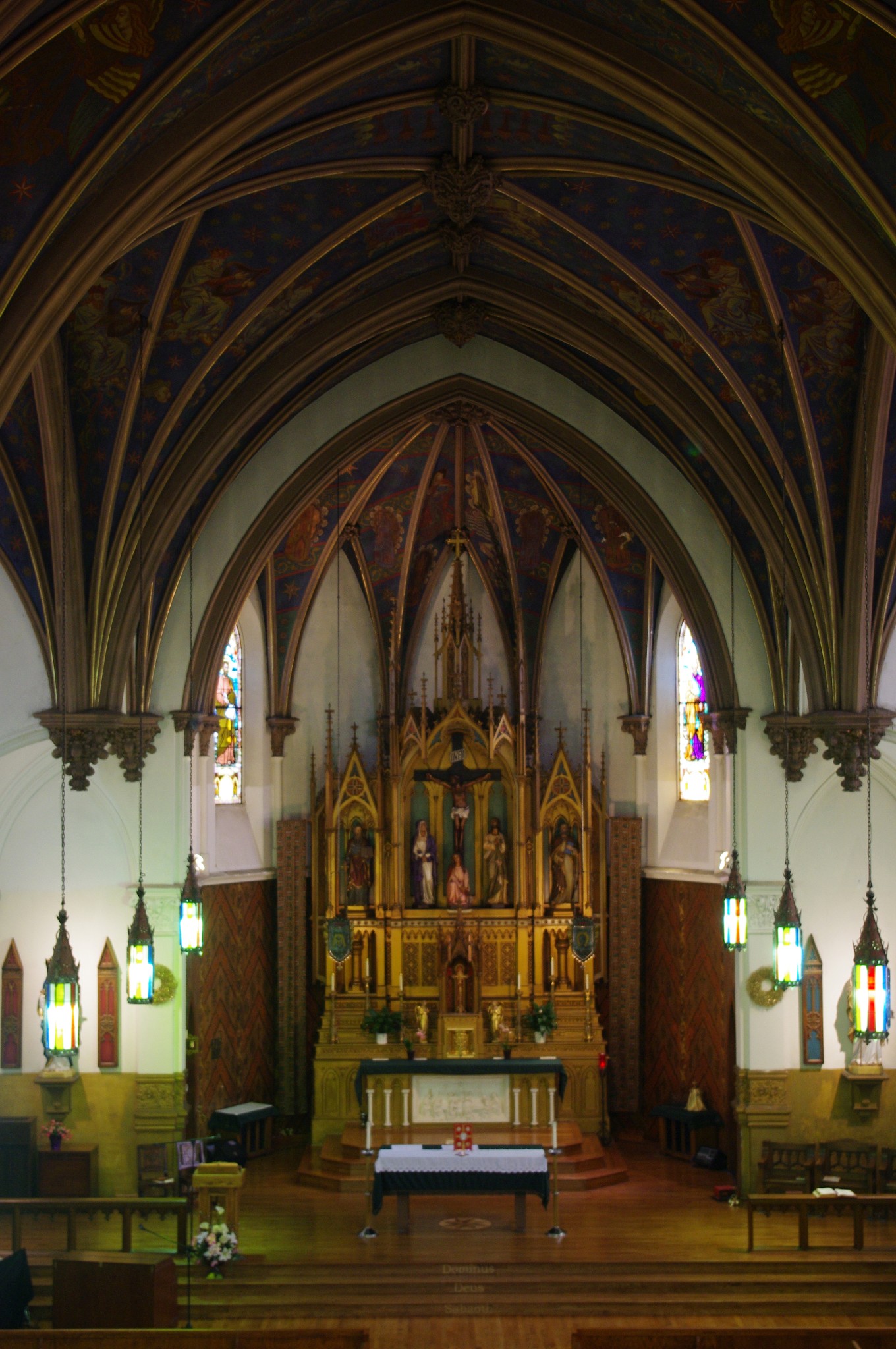 Interior perspective from the organ loft looking toward the ornate Gothic altar and blue ribbed vaulted ceiling.