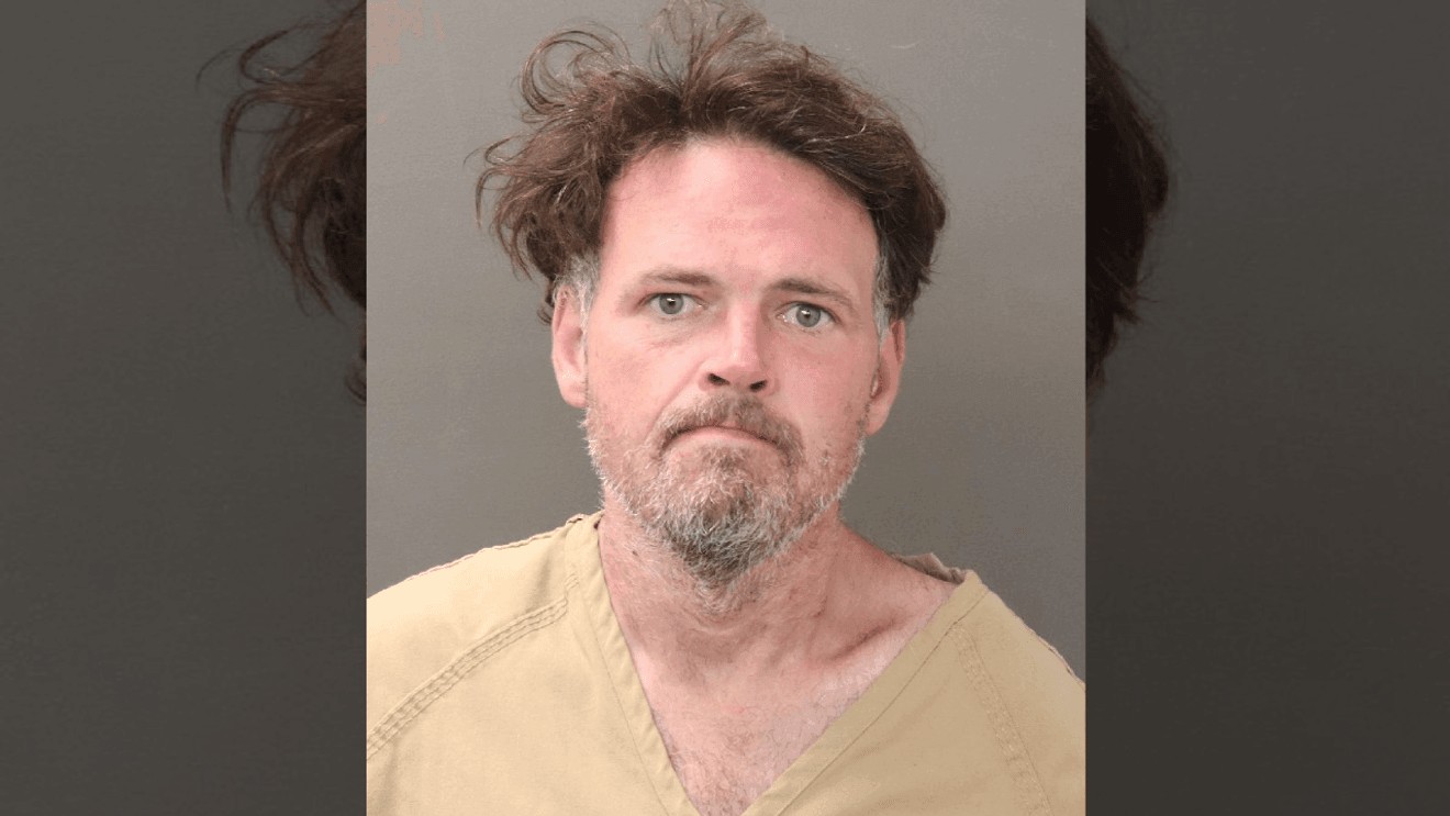 Mugshot of Joshua Bays with brown hair, blue-gray eyes, and a graying beard, wearing a tan inmate shirt.