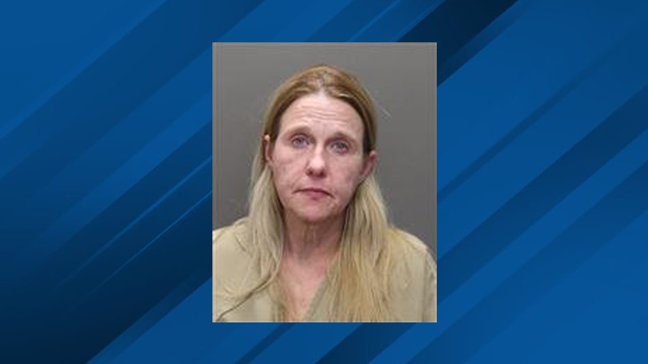 Booking mugshot of Tammra Straughter centered against a blue broadcast graphic backdrop.