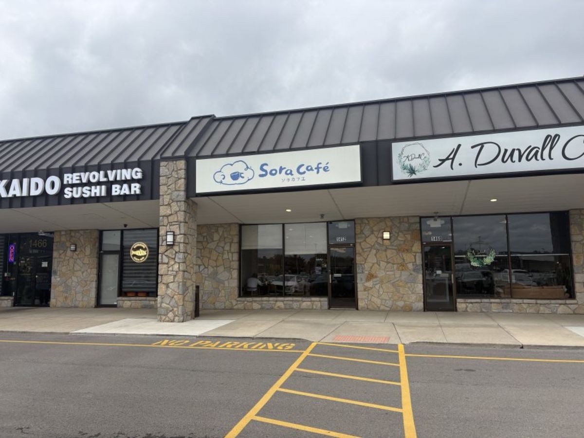 Exterior of Sora Café storefront at 1462 Bethel Road with sign and stone masonry wall between neighboring storefronts.