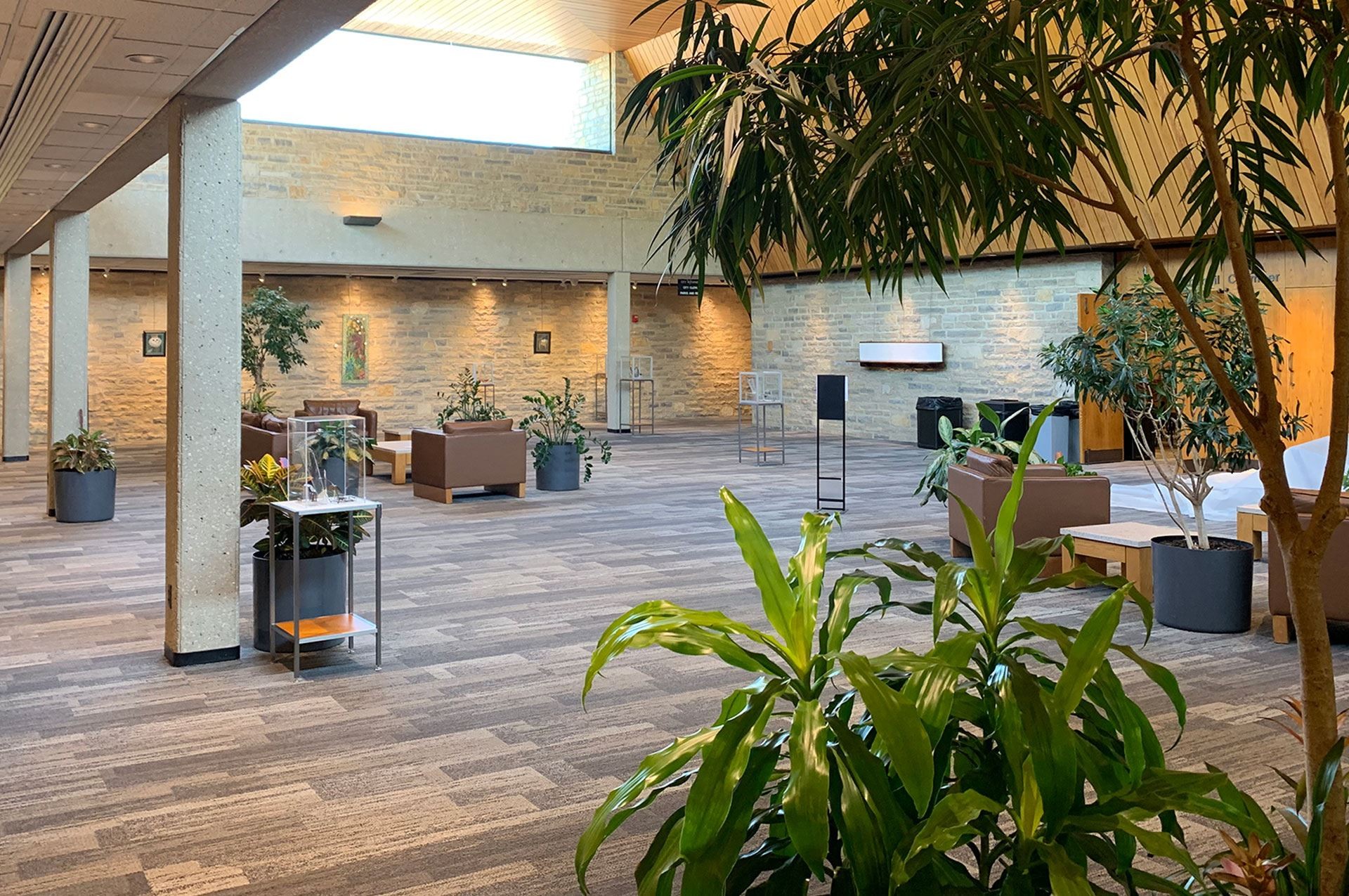 Interior view of the Upper Arlington Municipal Services Center concourse atrium with stone walls, skylights, lounge seating, and an entrance marked Council Chamber.